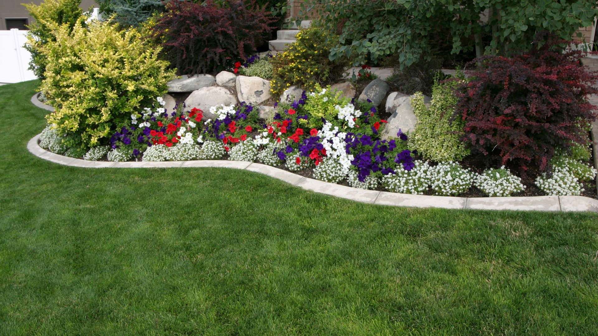 Curved landscape bed finished with fresh mulch and flowering plants